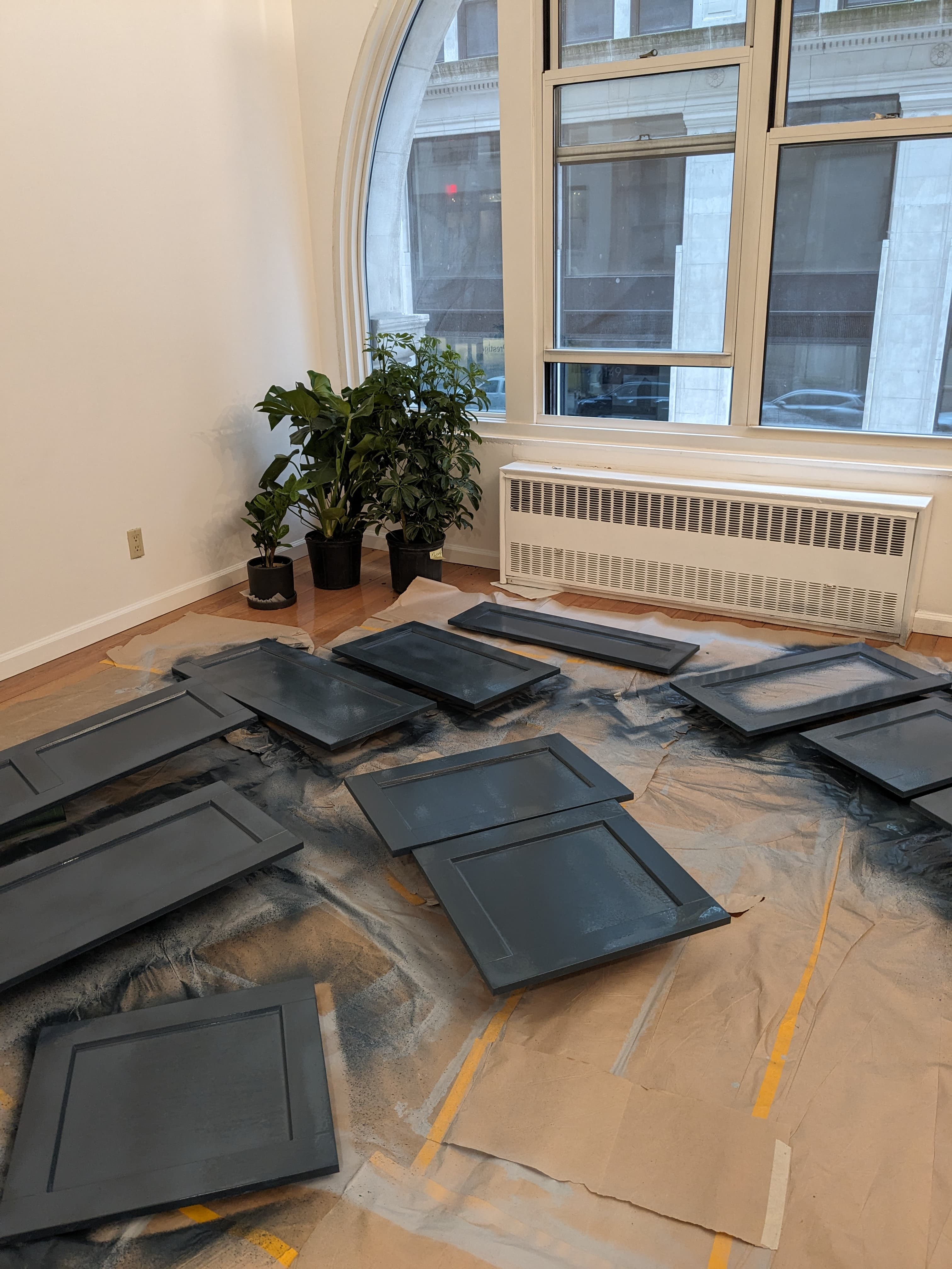 Fourteen cabinet doors, spray-painted on the living room floor.